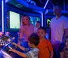 A family enjoys time together in a vibrantly colored room where a young child and a woman play with an old-fashioned telephone and another child and a man interact with a vintage television
