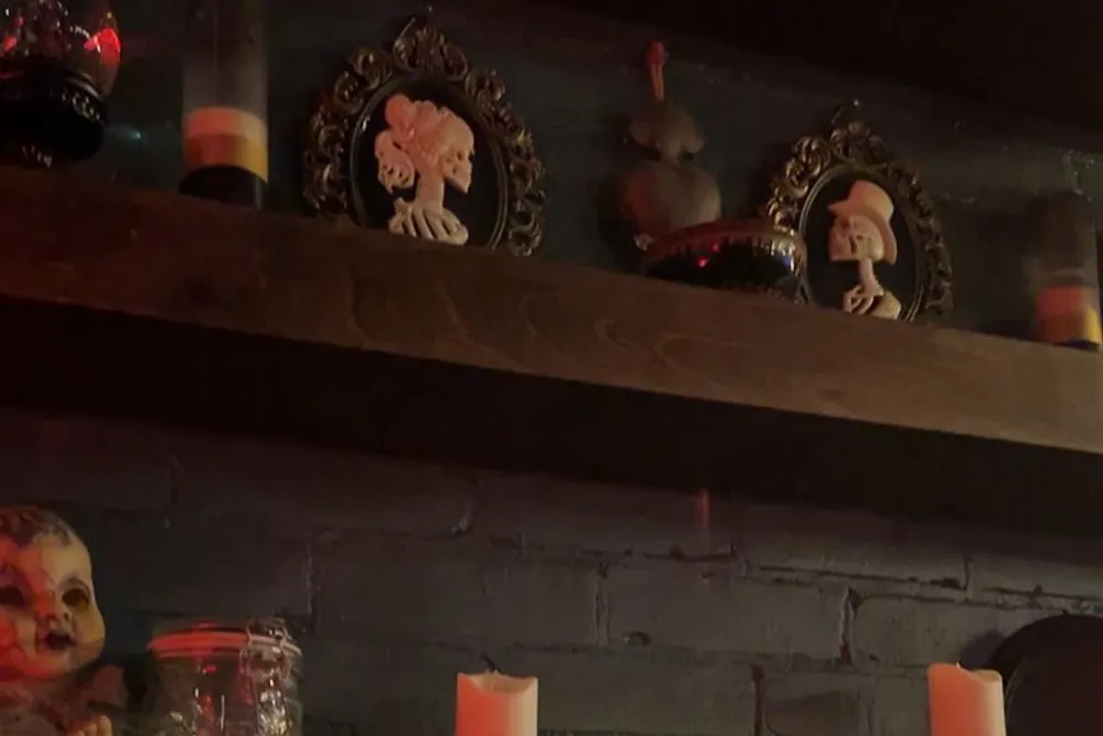 The image shows a dark eerie shelf adorned with Halloween-themed decor including ornate frames a doll-like figure and candles