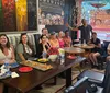 A group of people are smiling and posing for a photo in a colorful restaurant with artwork on the walls and food on their tables