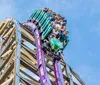 Thrilled riders are captured mid-air on a roller coaster with expressions of excitement and joy against a clear blue sky