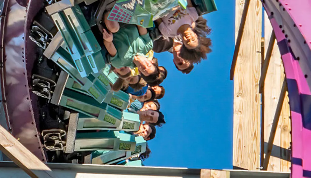 Thrilled riders are captured mid-air on a roller coaster with expressions of excitement and joy against a clear blue sky