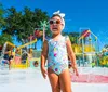 Two joyful children are sliding down a colorful water slide on a sunny day