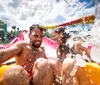 A man and a woman are joyfully riding down a water slide at a water park with splashes of water around them