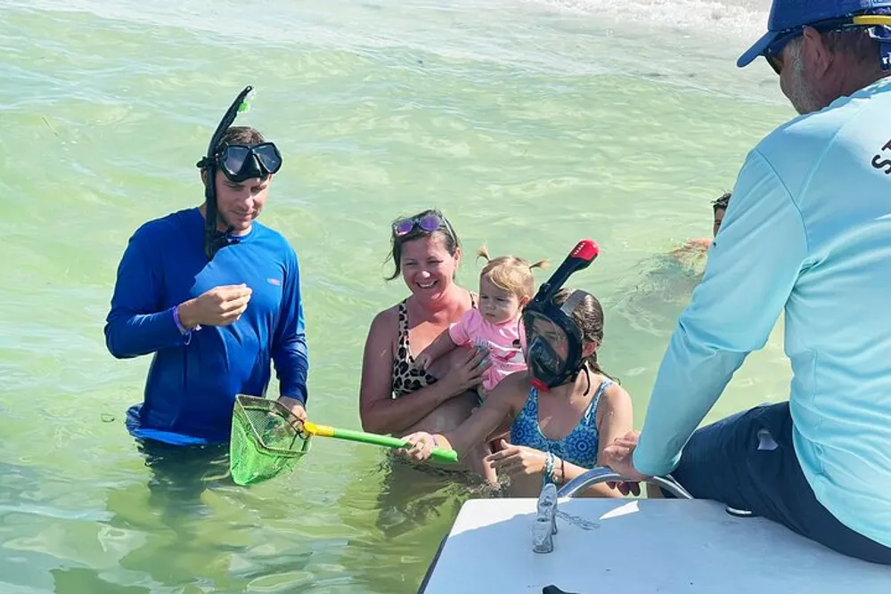 A group of people some wearing snorkeling gear are standing in shallow water possibly engaged in a guided aquatic activity or learning experience