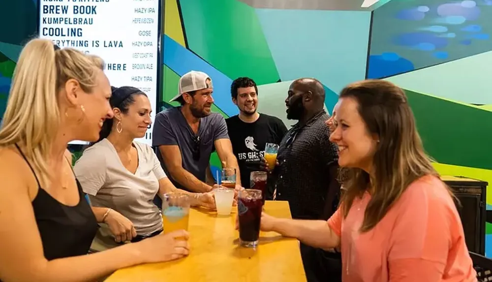 A group of people are enjoying drinks and conversation at a bar with vibrant interior decor