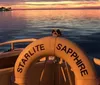 The image displays a large white luxury yacht named StarLite Sapphire cruising on calm blue waters with seafront buildings in the background