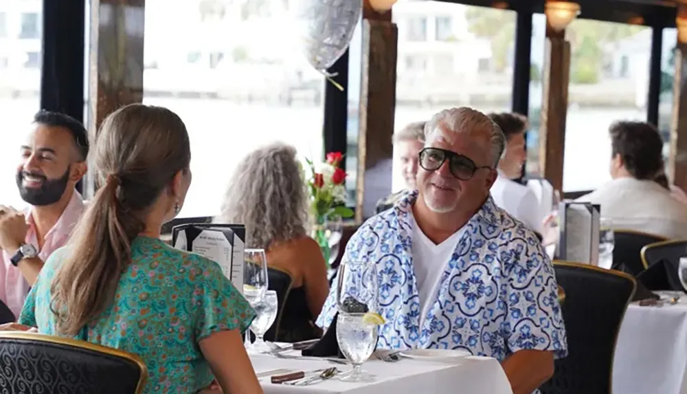 A group of people are enjoying a meal and conversation in a restaurant with large windows