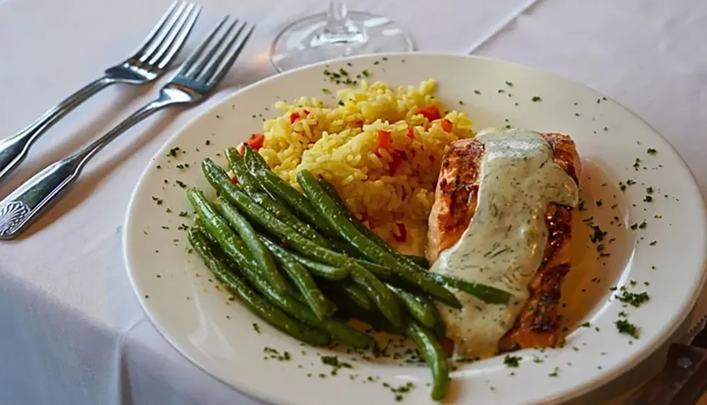 The image shows a plated meal consisting of grilled salmon topped with sauce accompanied by green beans and seasoned rice