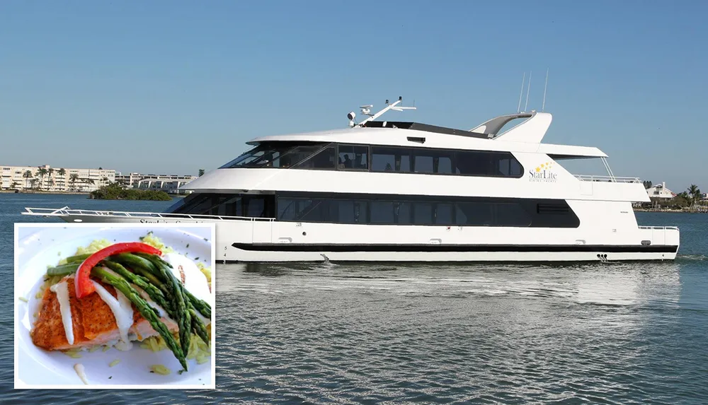 The image displays a large white luxury yacht named StarLite Sapphire cruising on calm blue waters with seafront buildings in the background