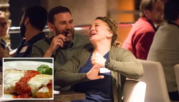 Two people are sharing a jovial moment with laughter at a social gathering.