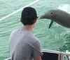 A person is watching a dolphin leaping out of the water near the side of a boat