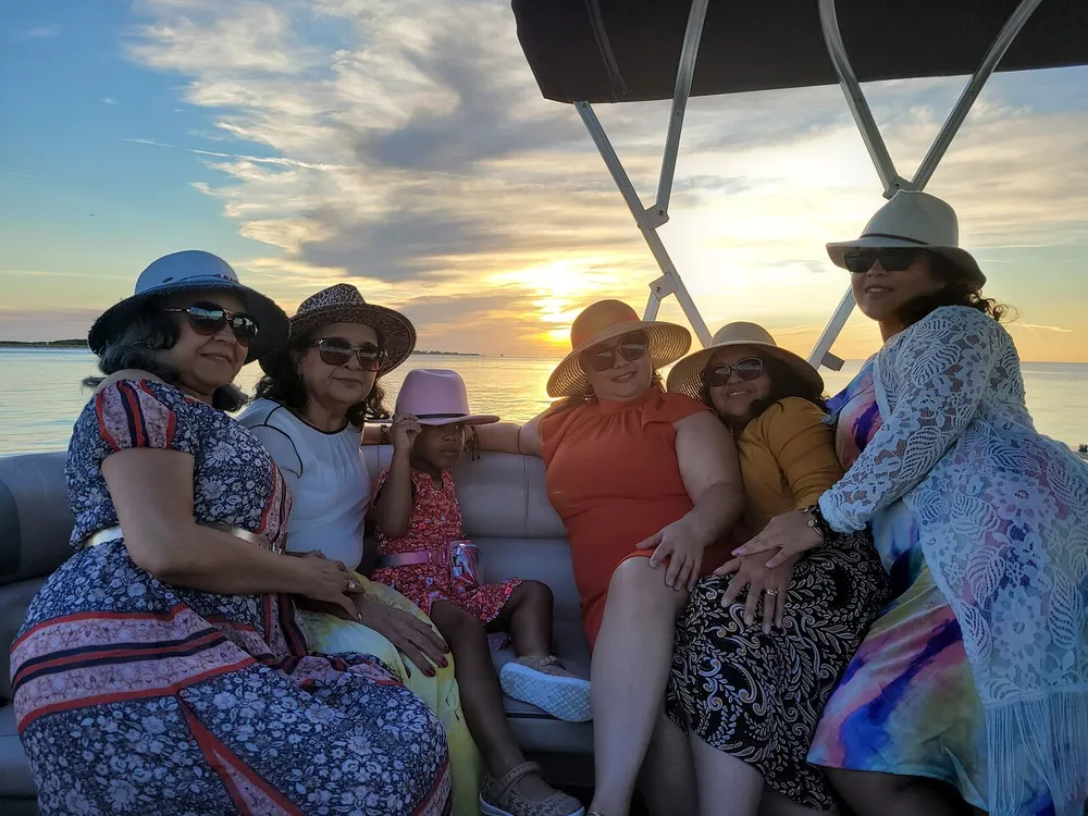 A group of people is enjoying a boat ride at sunset creating a serene and cheerful atmosphere