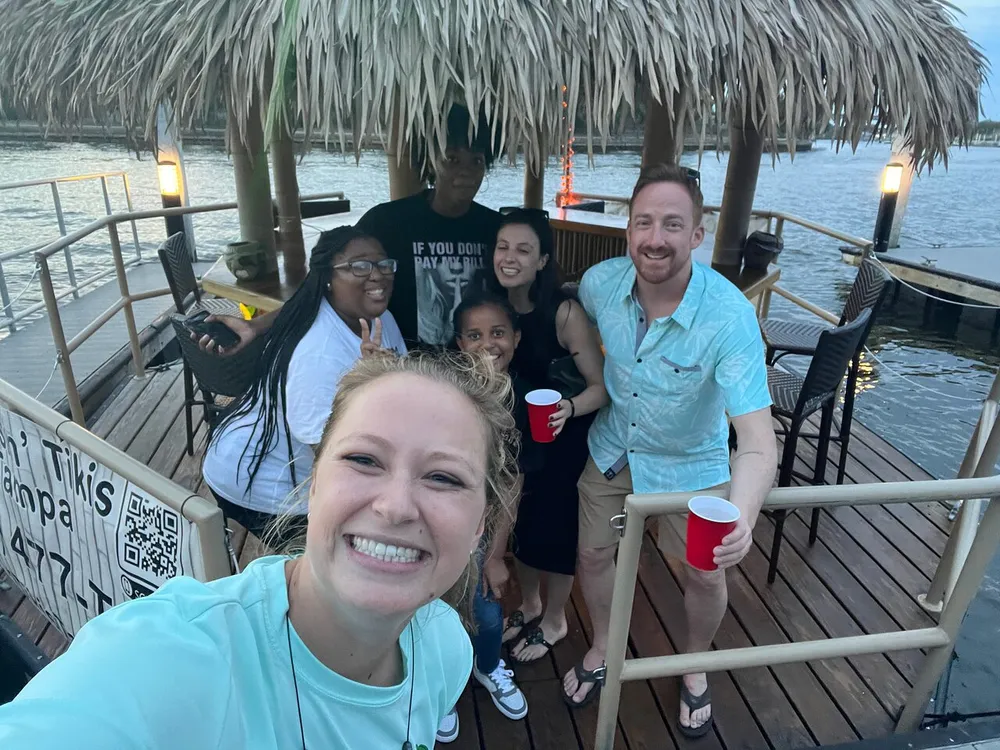 A group of cheerful people posing for a selfie on a tiki-themed boat bar