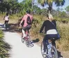 Three people are standing on a wooded trail with their bicycles smiling for the camera