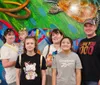 A group of six individuals likely a family is posing for a photo with a vibrant underwater-themed mural featuring a large turtle in the background