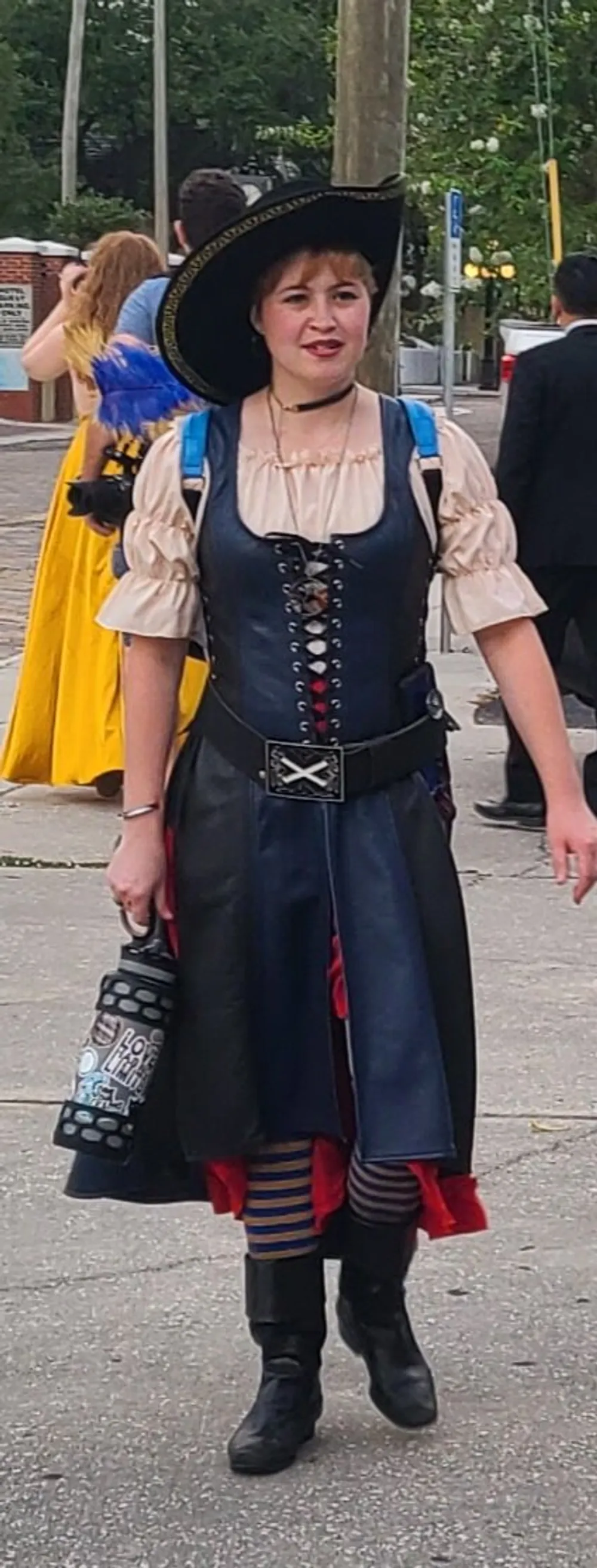 A person is dressed in pirate-inspired attire complete with a tricorn hat and a corset at an outdoor event