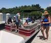 A group of people are preparing for a day on the water with one person standing on the dock next to a pontoon boat filled with supplies and passengers