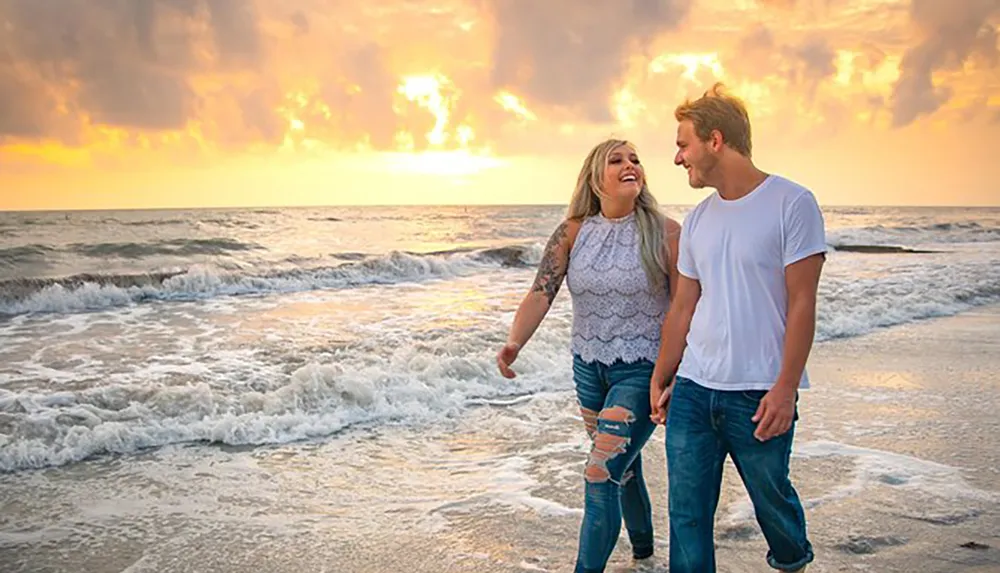 A happy couple is walking along the beach enjoying a beautiful sunset over the ocean