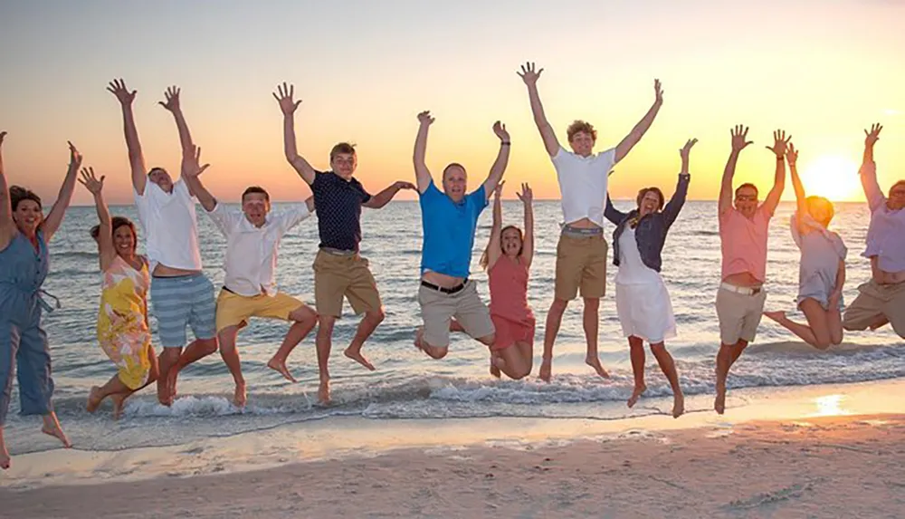 A group of people are joyfully jumping on a beach at sunset