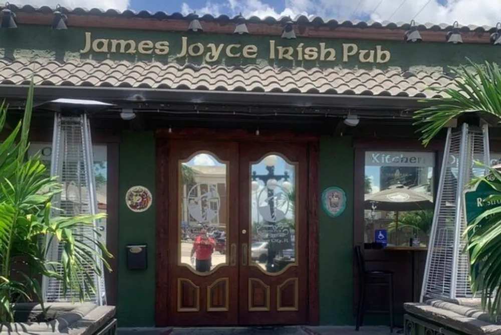 The image shows the entrance of James Joyce Irish Pub with ornate wooden doors traditional Irish-themed decoration and a green awning with the establishments name