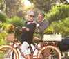 A happy couple shares an affectionate moment on a bicycle surrounded by lush greenery in a sunlit park