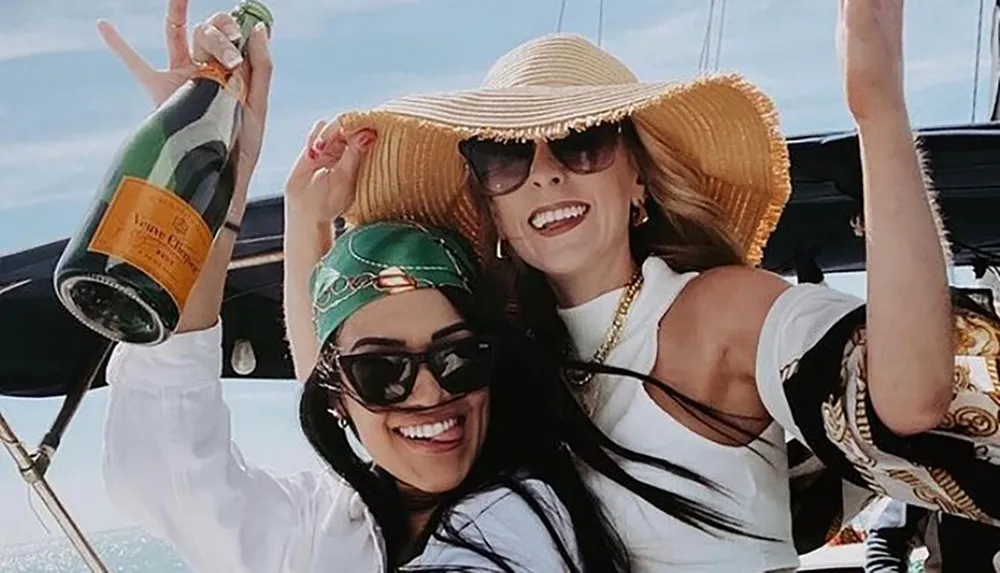 Two women are joyfully celebrating with a bottle of champagne on a boat