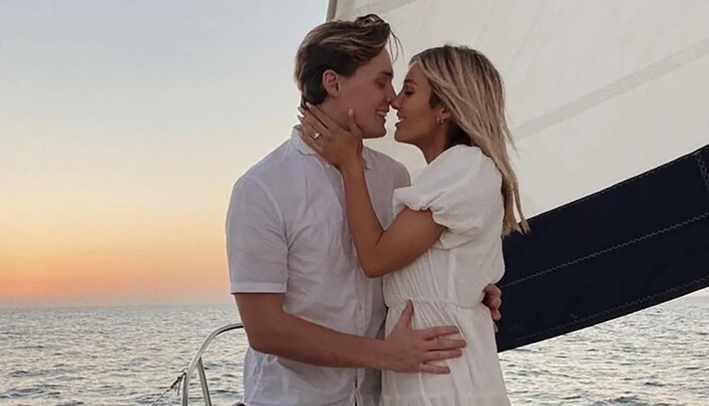 A couple is sharing an intimate moment on a sailboat at sunset