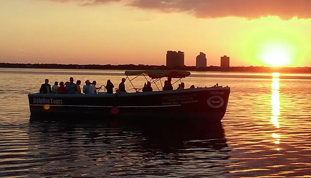 A group of people are enjoying a boat tour at sunset with the golden light reflecting off the water