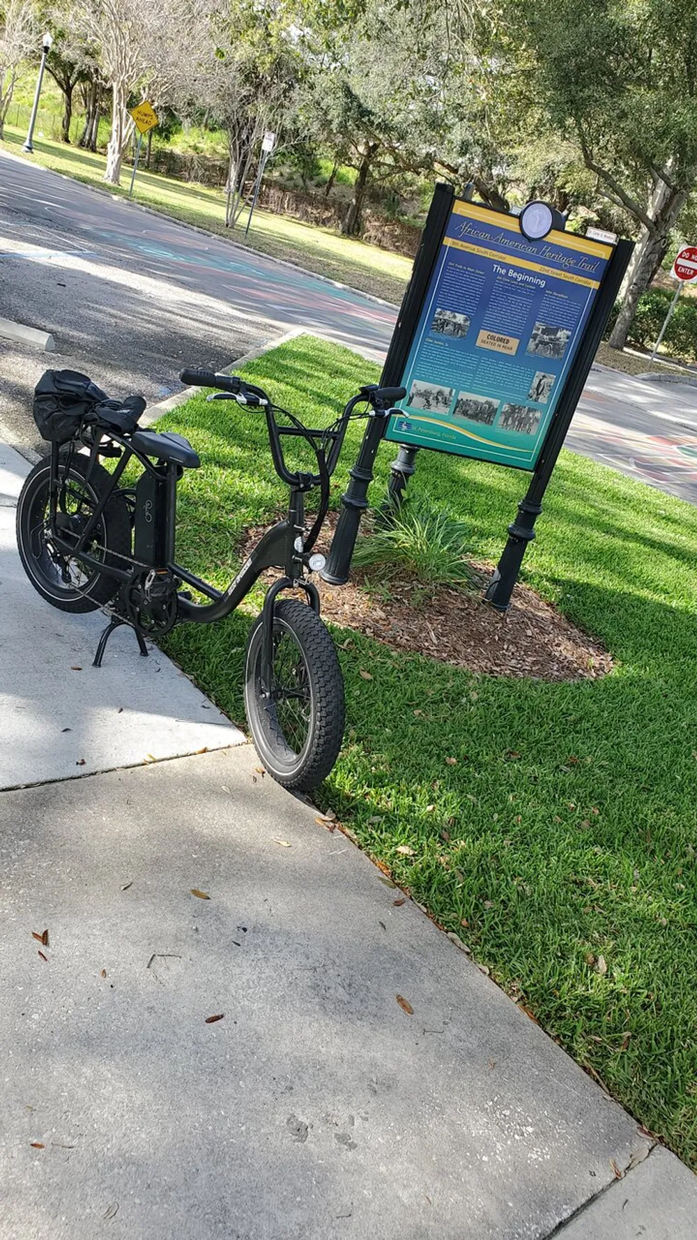 An electric bicycle is parked beside an informational signpost about the African American Heritage Trail