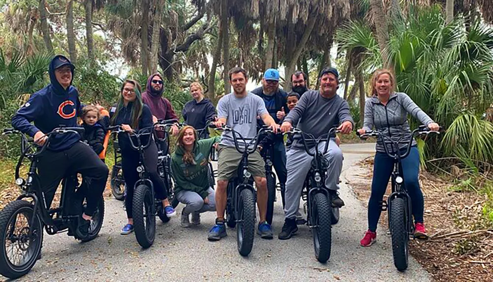 A group of happy people posing with their bicycles on a tree-lined path