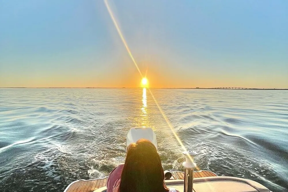 A person enjoys a serene boat ride on a calm sea under a captivating sunset