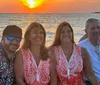 Four smiling individuals are enjoying a boat ride at sunset