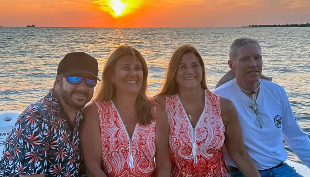 Four smiling individuals are enjoying a boat ride at sunset