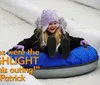 A joyful child slides down a snowy hill on a blue inflatable snow tube wearing a winter jacket and a knitted hat