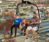 A man and two children are riding on a chairlift with a cityscape in the background