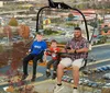 A man and two children are riding on a chairlift with a cityscape in the background