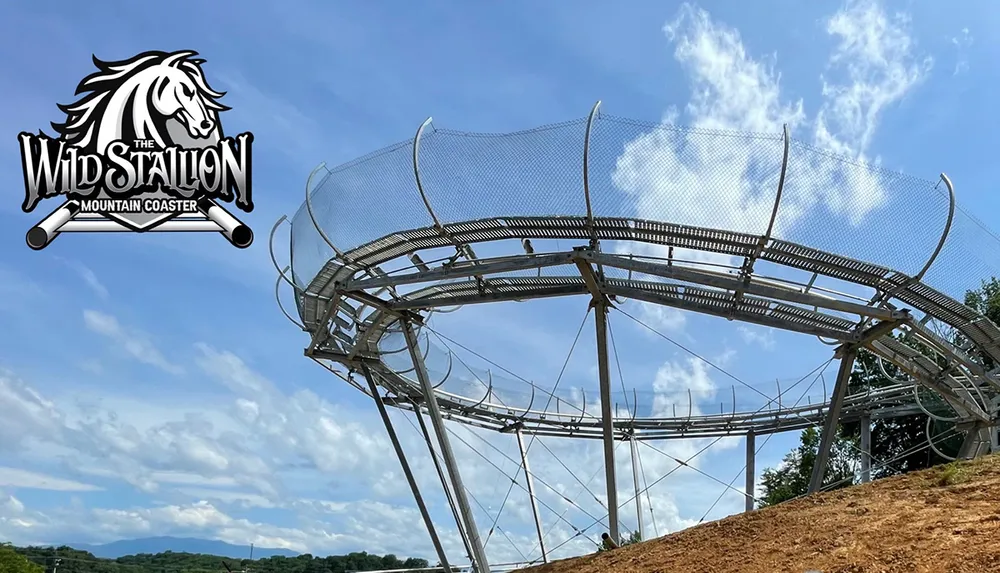 The image shows a section of the Wild Stallion Mountain Coaster a metal alpine coaster with twists and turns situated in a scenic outdoor location with a clear sky above