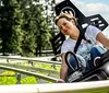 A person is enjoying a ride on an alpine coaster amidst green surroundings on a sunny day