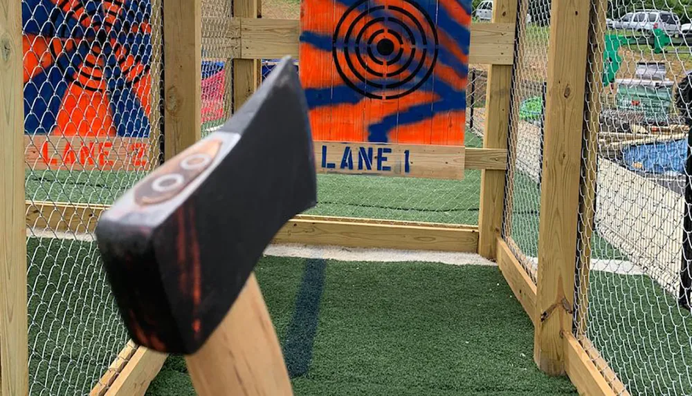 A hatchet is poised mid-throw in front of a colorful target board in an ax-throwing lane