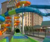 A colorful outdoor water slide complex snakes its way through the frame with a hotel in the background