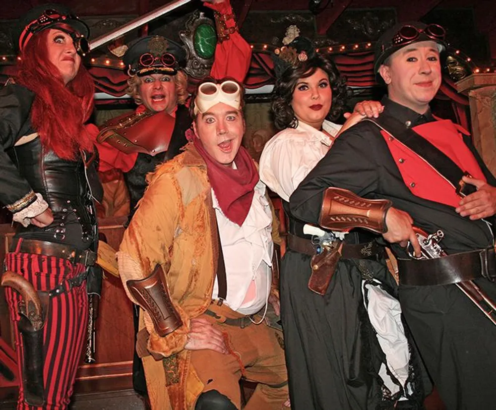 A group of people are dressed in colorful and eclectic steampunk costumes posing playfully for the photo with exaggerated expressions and dynamic postures