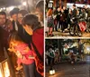 A group of people are gathered around a lantern outdoors at night paying attention to a person who appears to be leading a tour or telling a story