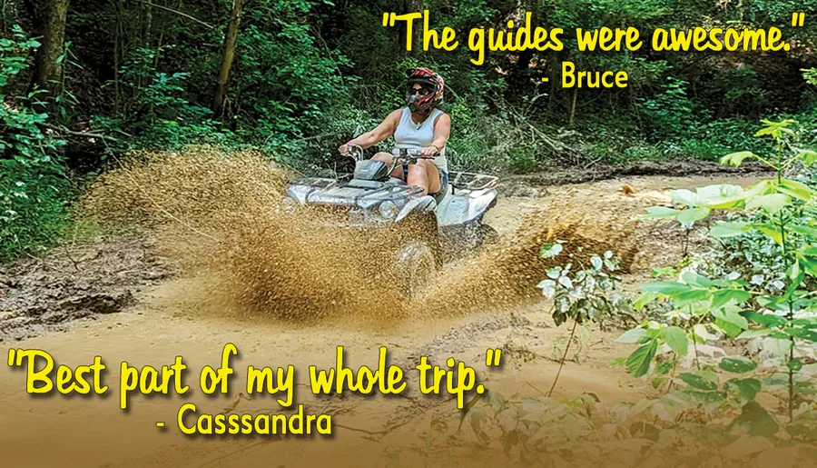 A person is riding an ATV through a muddy trail, splashing water and mud as they go.