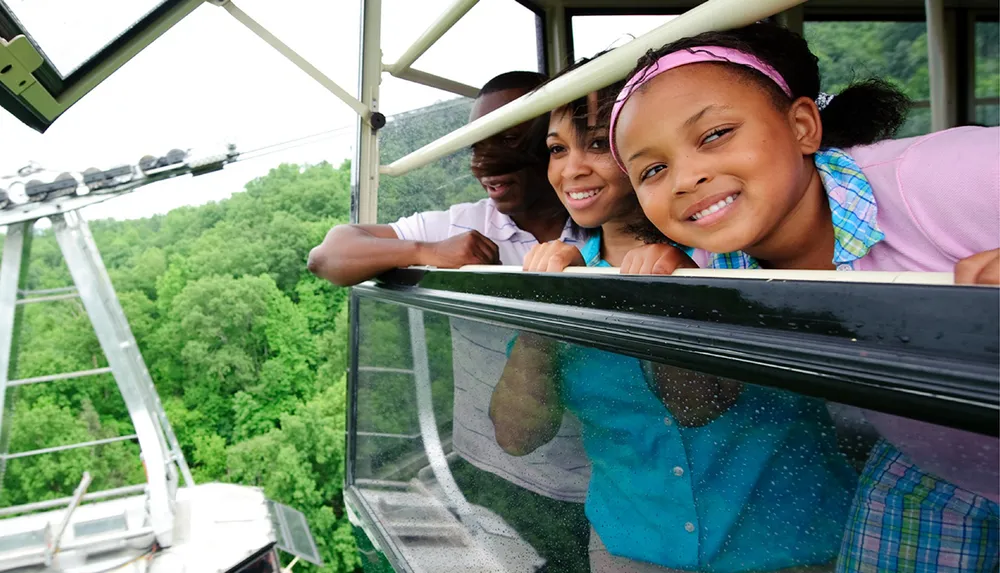 Three individuals are enjoying a scenic view from inside a cable car