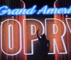 A group of performers is posing energetically on stage in front of a large sign with a positive quote about their singing and an inset image of a meal featuring chicken mashed potatoes and green beans