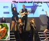 A group of performers is posing energetically on stage in front of a large sign with a positive quote about their singing and an inset image of a meal featuring chicken mashed potatoes and green beans