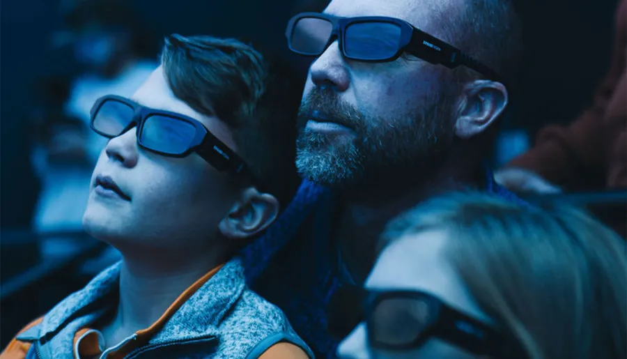 A man and a young boy wearing 3D glasses are watching something intently.