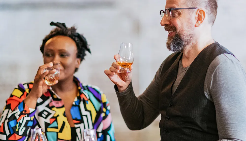 Two people are enjoying a beverage together smiling and holding glasses