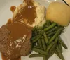 A performer in a gold jacket sings on stage with background images while an inset shows a plate of mashed potatoes green beans and a meat dish with gravy