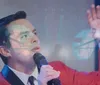 A person in a red jacket is singing into a microphone next to text that says Jersey Voice The Frankie Valli Tribute